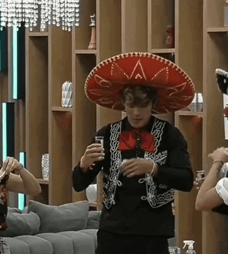 a man wearing a sombrero is holding a drink