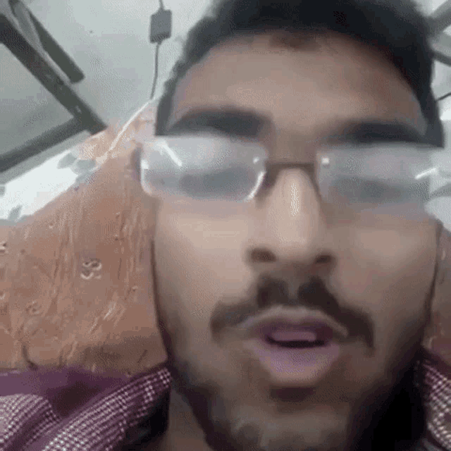 a man with glasses and a beard is making a face .