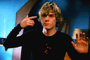 a man in a black shirt is pointing his finger at himself