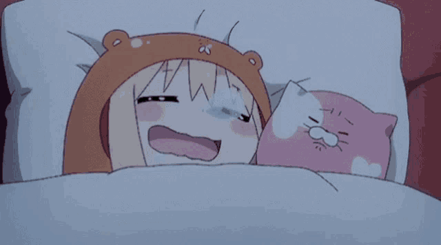 a girl in a bear hat is laying in bed with a pink cat pillow