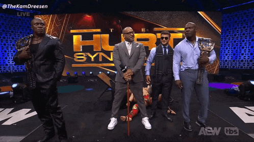 a group of men are standing on a stage with a woman laying on the floor .