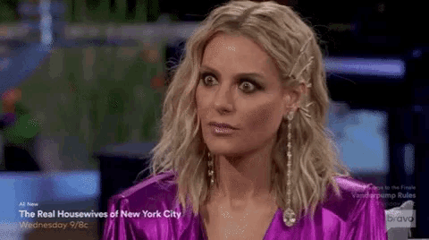 a woman wearing a purple dress and earrings is making a funny face .
