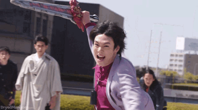 a man is holding a large sword in front of a group of people .