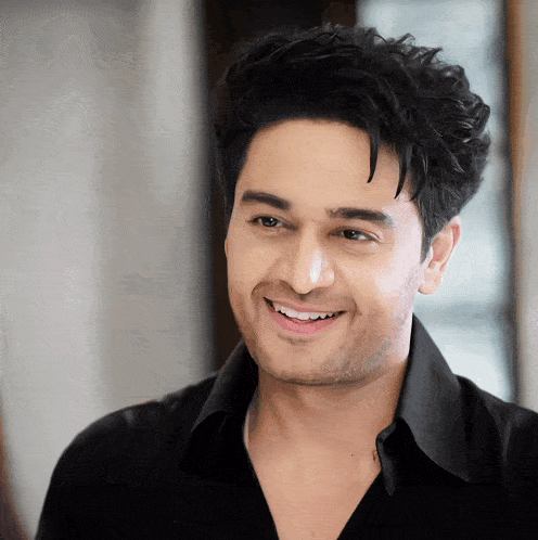 a man wearing a black shirt is smiling and looking at the camera