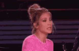 a woman in a pink dress is talking into a microphone .