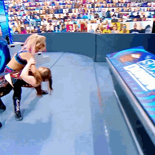 two women are wrestling in front of a crowd and one of them is wearing a shirt that says ' smackdown ' on it