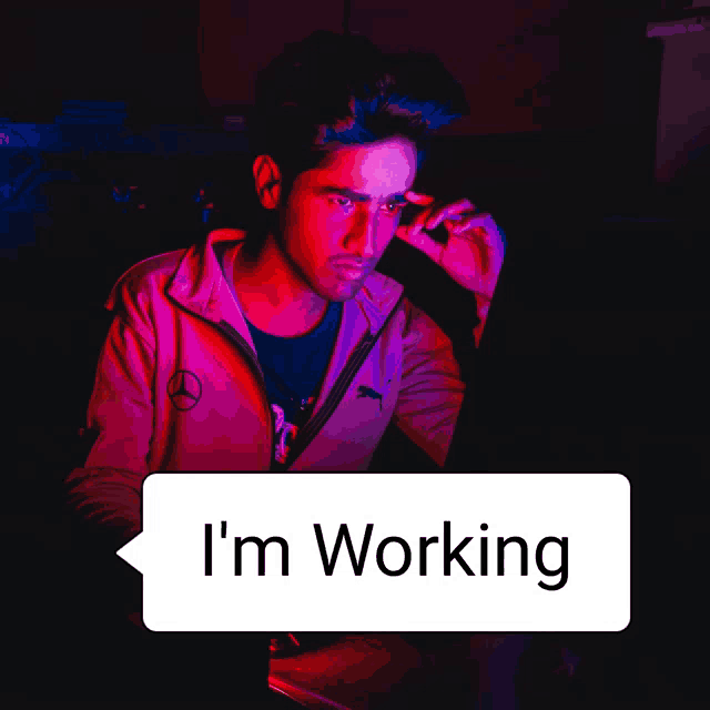 a man sitting in front of a computer with a speech bubble saying " i 'm working "