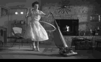 a woman is hula hooping while using a vacuum cleaner .