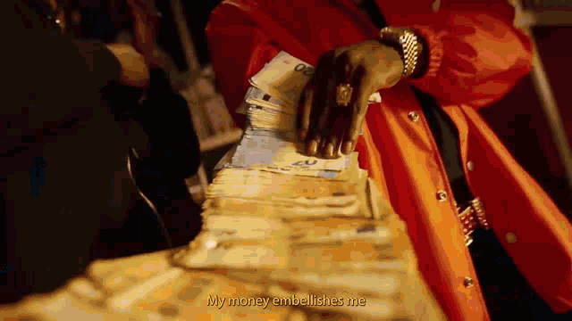 a man in an orange jacket is holding a large stack of money ..