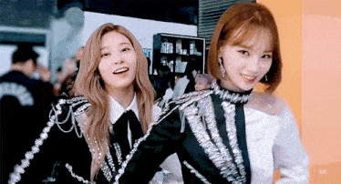 two girls are standing next to each other and one of them has a sticker on her shirt that says ask