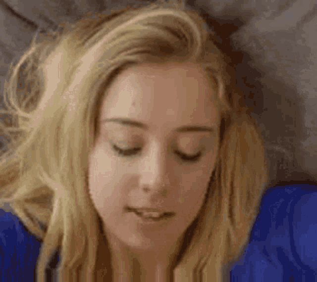 a blonde woman is laying on a couch with her eyes closed .