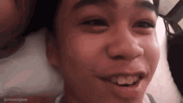 a close up of a person 's face while laying on a bed and smiling .