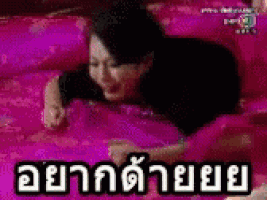 a woman is laying on a bed with a pink blanket and a pink pillow .