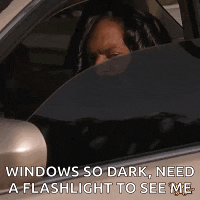 a woman is sitting in a car with her head out the window and a flashlight to see her .