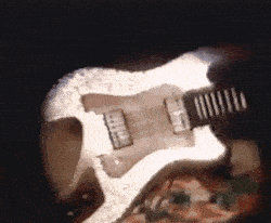 a person is playing an electric guitar in a dark room .