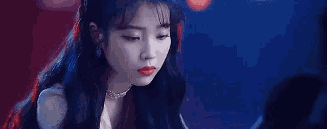 a woman with long black hair and red lipstick is sitting in front of a laptop computer .