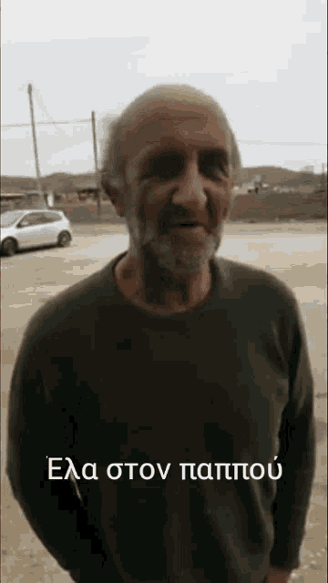 a man with a beard is wearing a green sweater with a foreign language written on the bottom