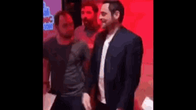 a man in a suit is standing next to another man in a black shirt .