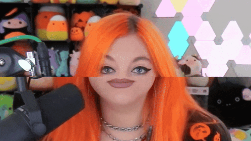 a woman with orange hair is making a funny face while standing in front of a microphone