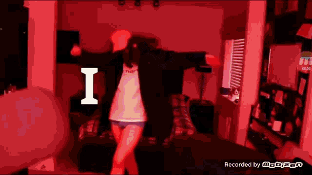 a woman is dancing in a red room with the letter i on the bottom