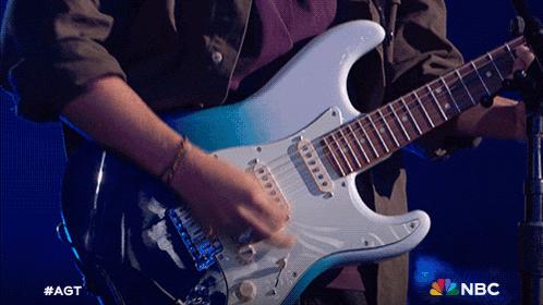 a man is playing a guitar in front of a microphone and the nbc logo