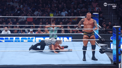 a man in a wrestling ring with a referee and a sign that says tnt sports