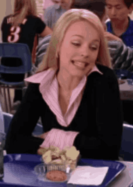 a woman is sitting at a table with a tray of food and a napkin .