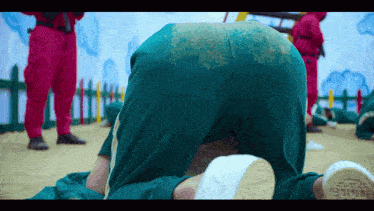 a person in green pants is kneeling down with their pants covered in sand