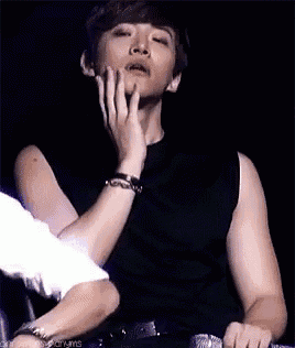 a man in a black shirt is touching his face with his hand .