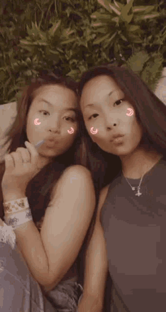 two young women are posing for a picture together with a straw in their mouth .