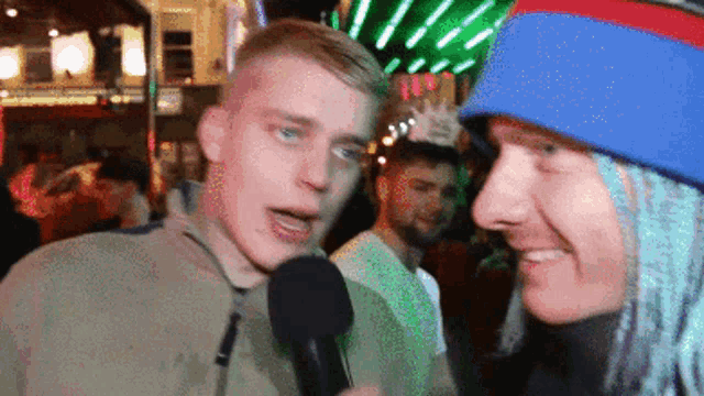 a man is talking into a microphone while wearing a blue and red hat