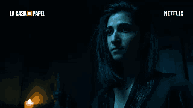 a woman in a dark room with a candle and a netflix logo behind her