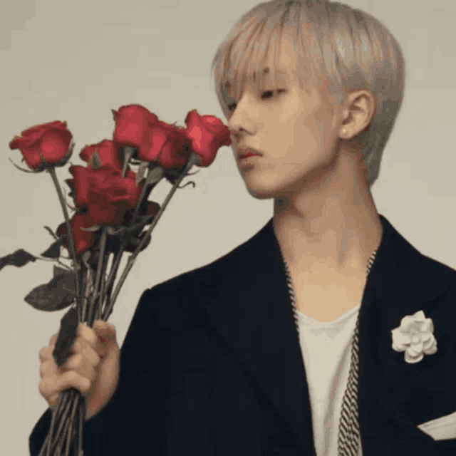 a man holding a bouquet of red roses in his hand