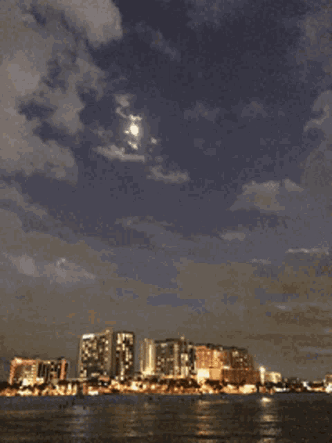 a city skyline with a full moon in the sky