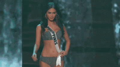 a woman in a bikini is standing on a stage wearing a sash with the word philippines on it .