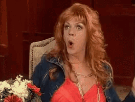 a woman with red hair is sitting in a chair with a bouquet of flowers .
