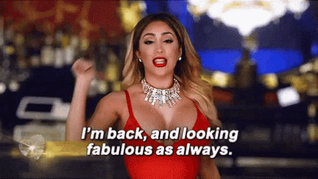 a woman in a red top and necklace is saying i 'm back and looking fabulous as always .