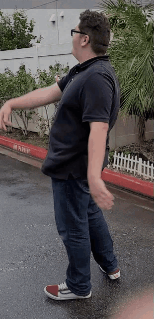 a man is standing in front of a red curb that says no parking