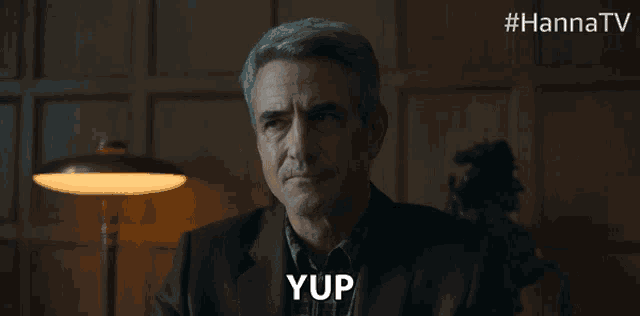 a man in a suit says yup in a dark room