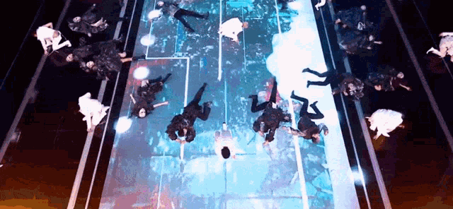 a group of people are dancing on a stage with a large screen behind them .