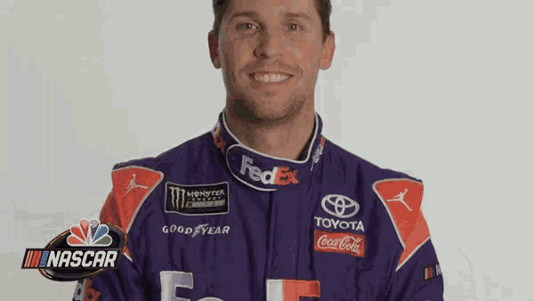 a man wearing a purple and orange racing suit is smiling for a picture .