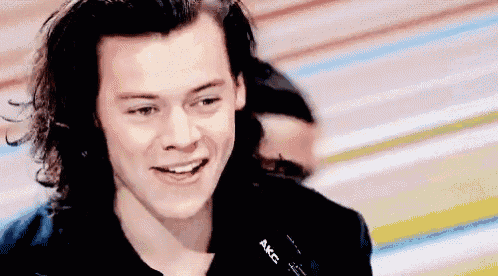 a close up of a man 's face with long hair smiling .