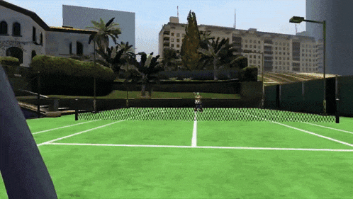 a person is playing tennis on a tennis court with buildings in the background