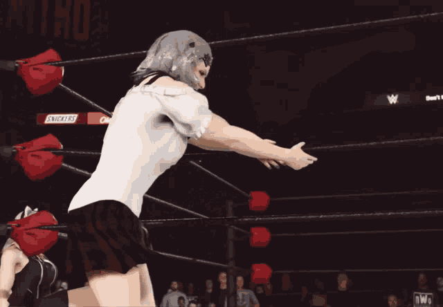a woman in a white shirt is in a wrestling ring with a snickers sign in the background