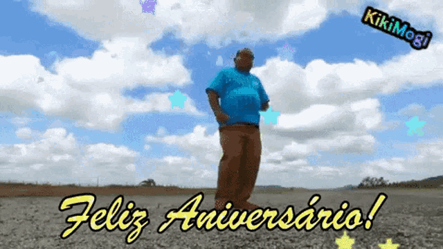 a man in a blue shirt is dancing in front of a cloudy sky with the words feliz aniversario on the bottom