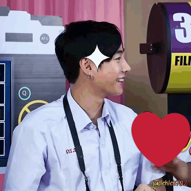 a man with a camera strap around his neck holds a red heart