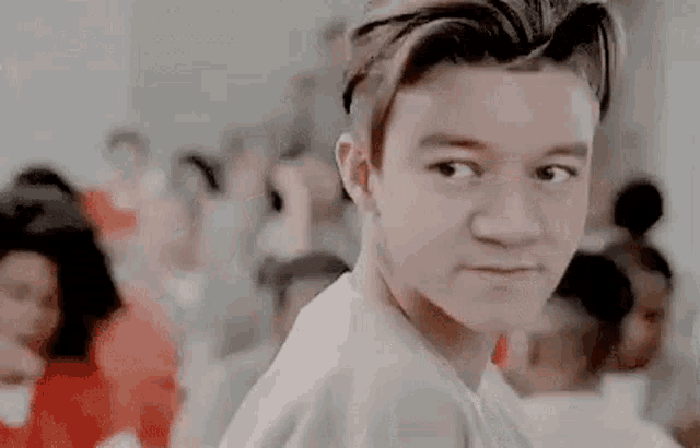 a young boy is looking at the camera in front of a crowd of people .