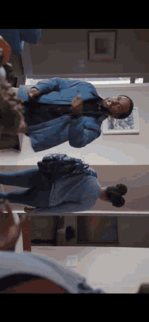 a man in a blue jacket is dancing in front of a mirror