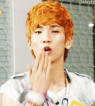 a man with orange hair is blowing a kiss with his hand