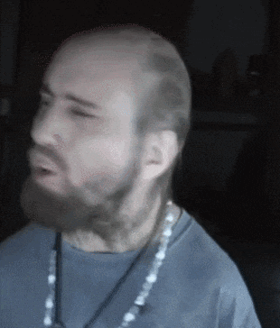 a bald man with a beard is wearing a blue shirt and a necklace